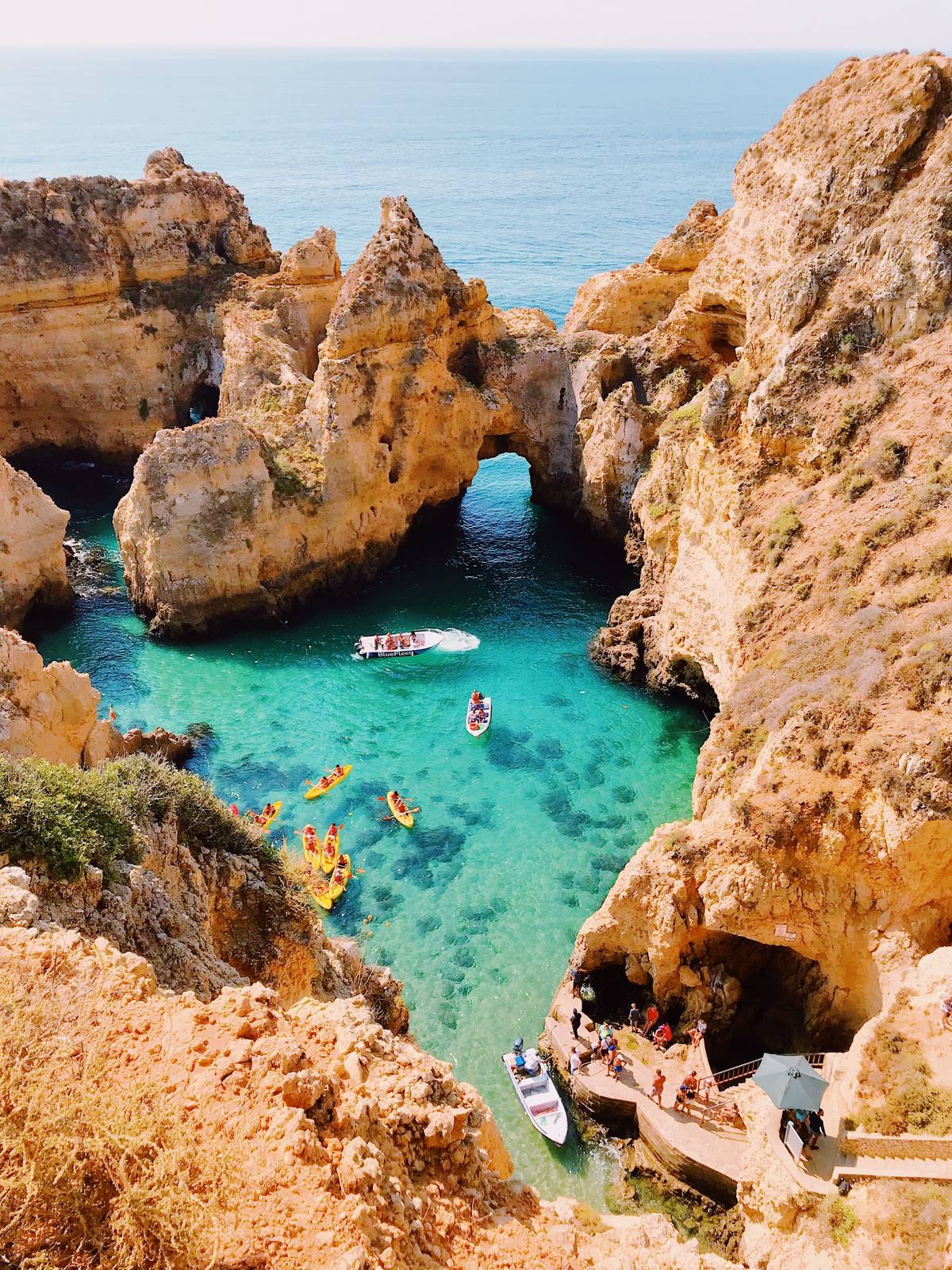Cala de aguas turquesa entre acantilados rocosos, con lanchas