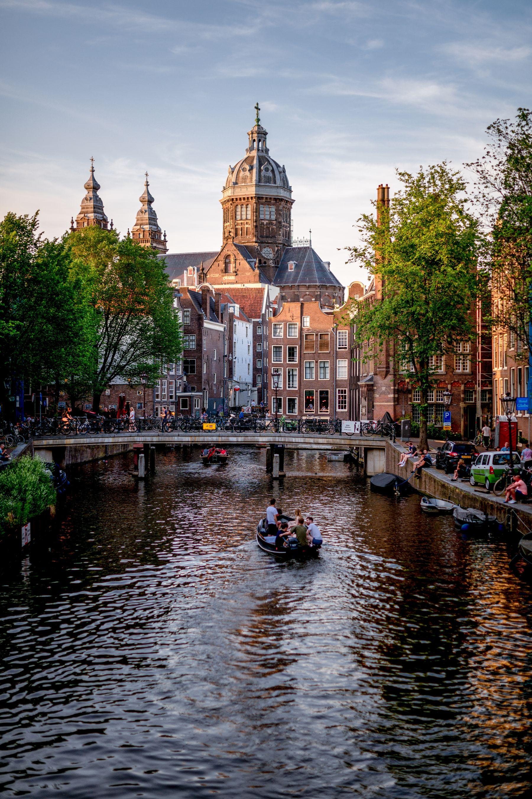 Canal de Ámsterdam con casas antiguas y una iglesia al fondo