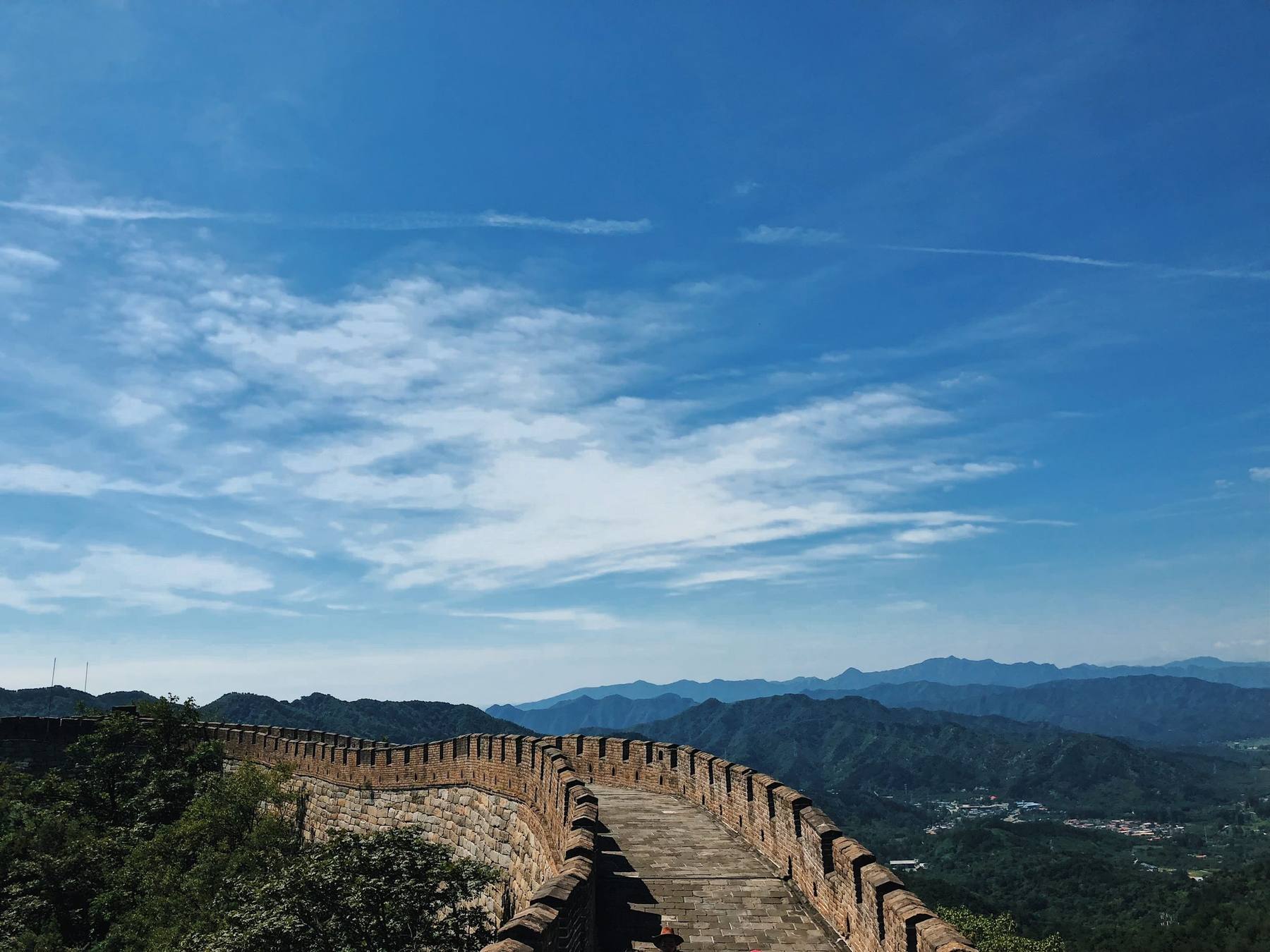 Tramo de la Gran Muralla China serpenteando entre montañas verdes bajo un cielo azul