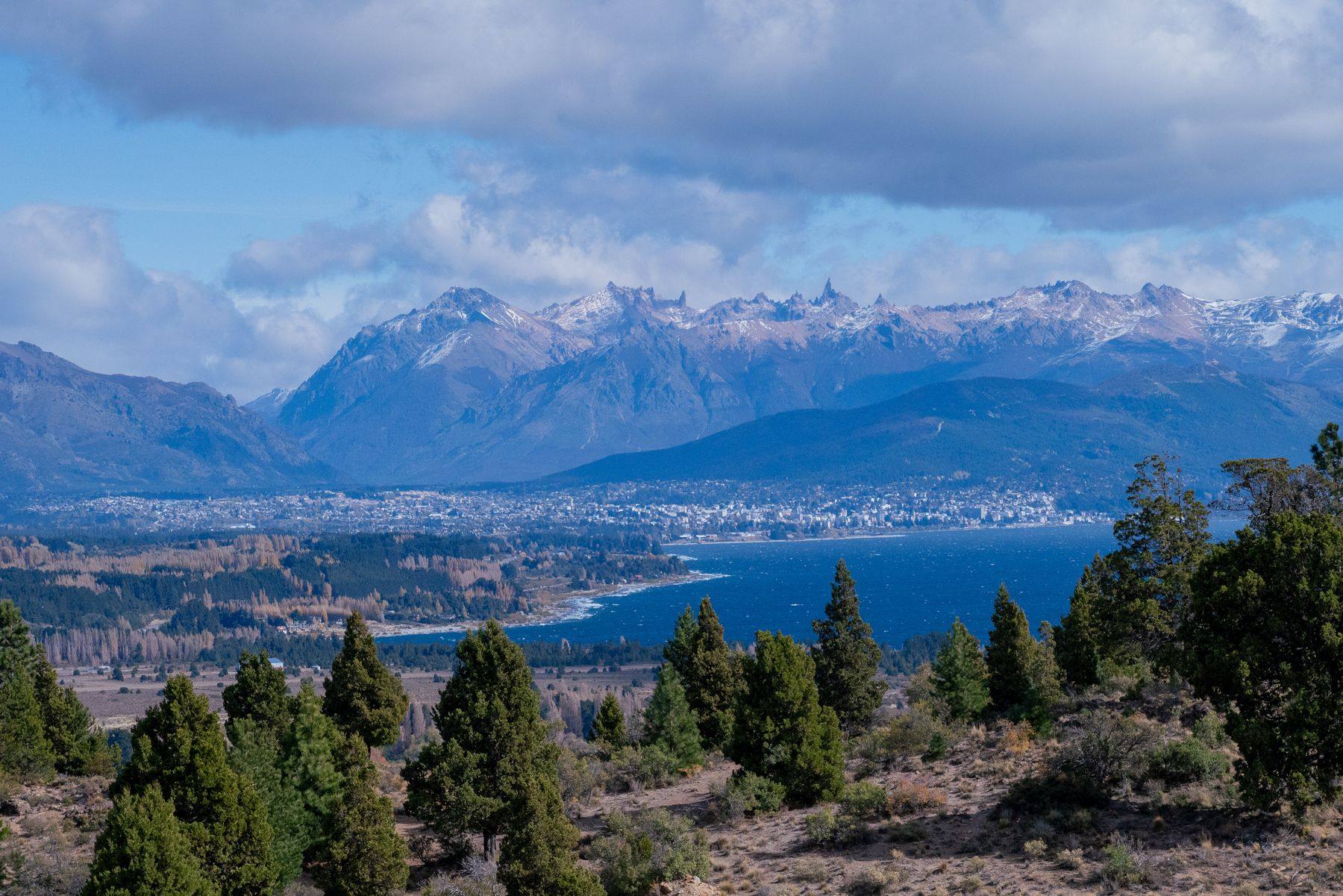 Lago Nahuel Huapi con la ciudad de Bariloche y la cordillera de los Andes al fondo, entre pinos