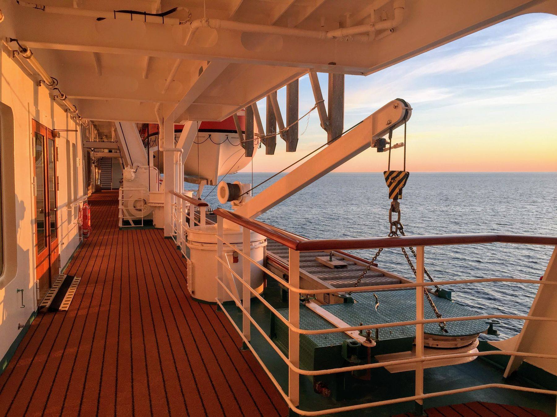 Cubierta de paseo de un crucero al atardecer, con el mar abierto de fondo