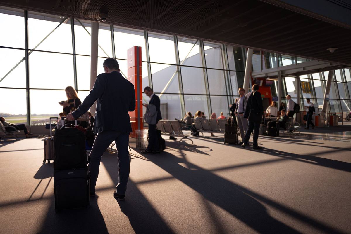 Viajero de traje con valija caminando por la terminal de un aeropuerto